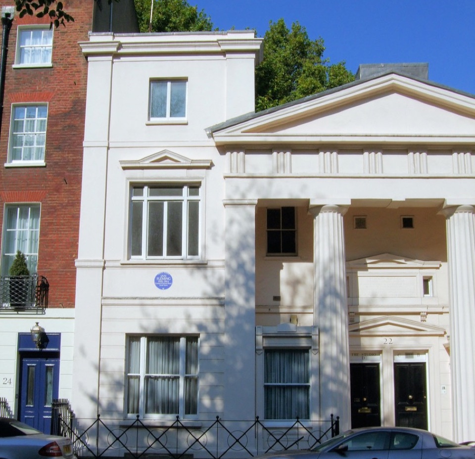 A white stucco house in Belgravia next to a brick house with a cast iron balcony