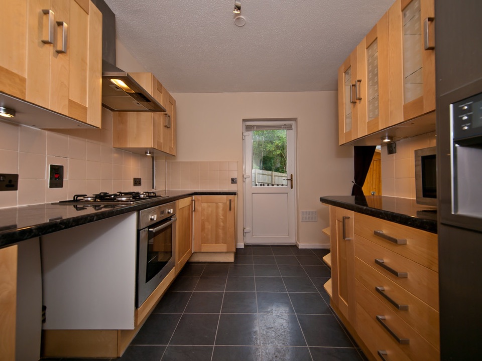 A galley kitchen in an English house with sockets along the worktop and a back door