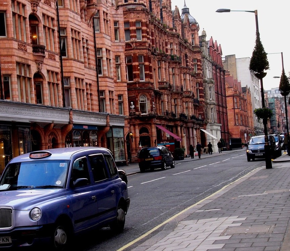A central London street of red terracotta mansion blocks above shops